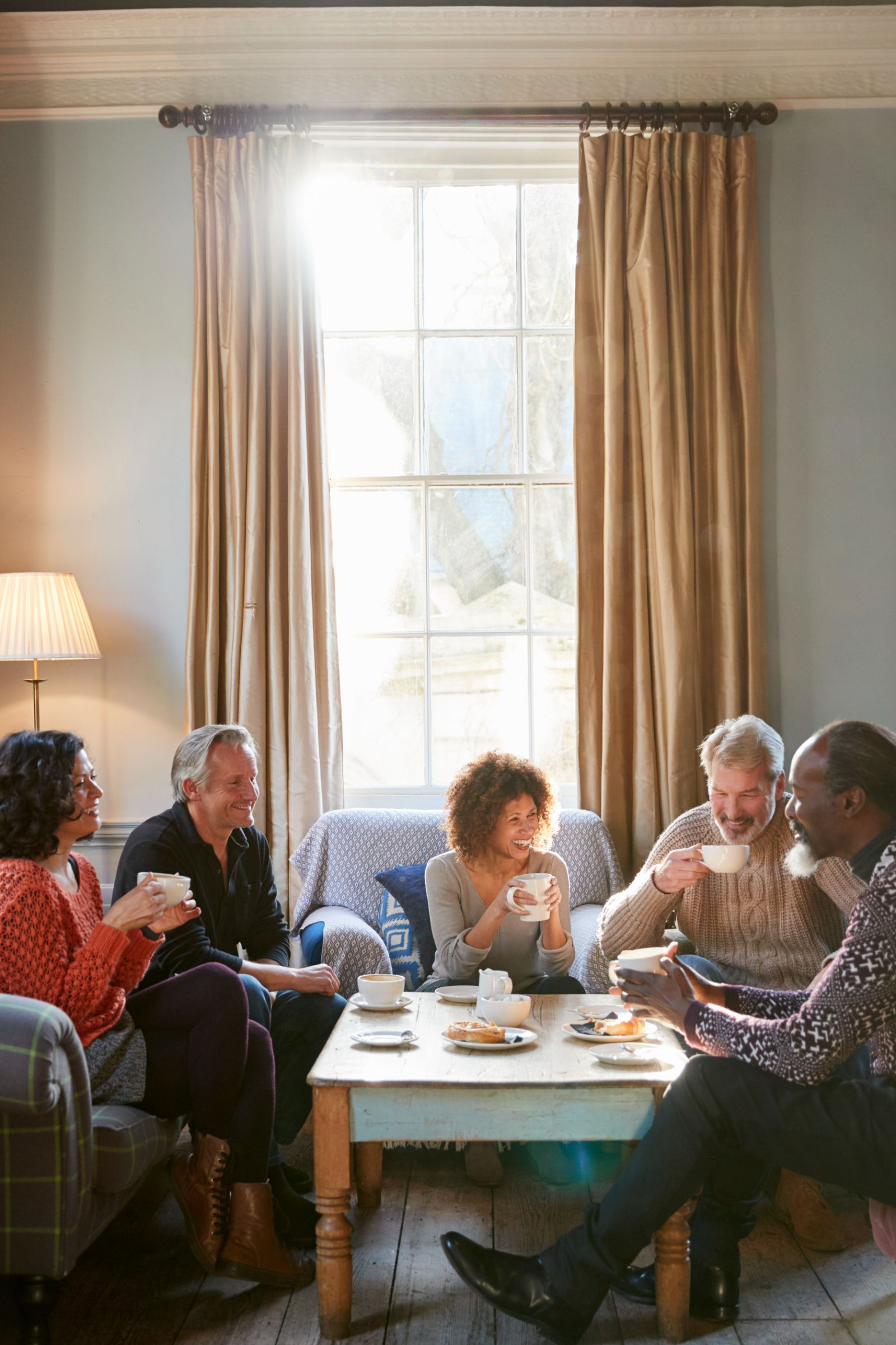 Friends sharing tea and laughing together in a sunlit living room