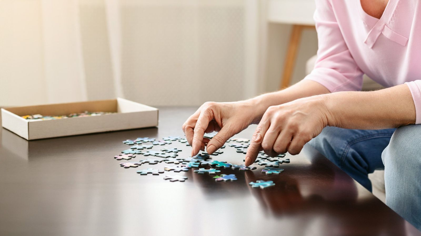 Hands assembling a jigsaw puzzle on a table at home